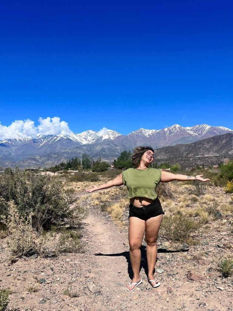emocionanda em Mendoza/Argentina com ps braços abertos e a Cordilheira dos Andes ao fundo